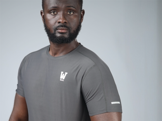 Man wearing a grey surge patterned active t-shirt with waaka logo and reflective strip on a plain background