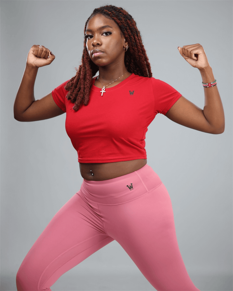 Person wearing a red crop top and pink leggings on a gray background