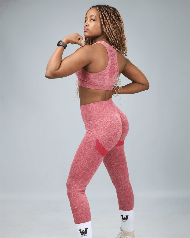 Person wearing a red athletic outfit on a gray background flexing muscle