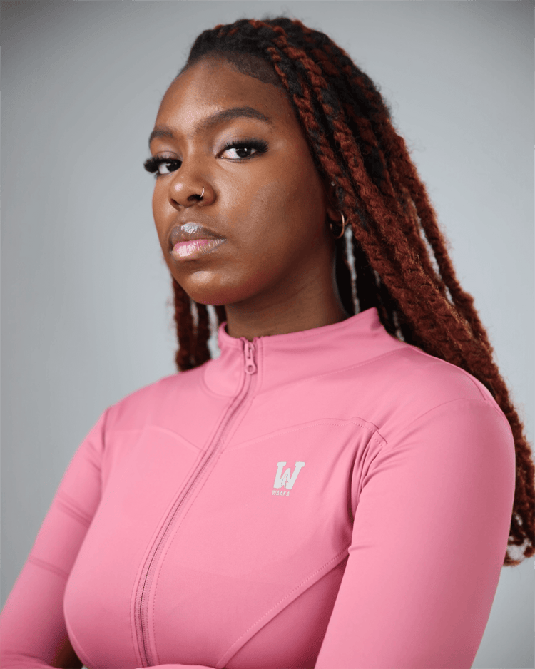 Woman wearing a pink long-sleeve top with a logo on a gray background