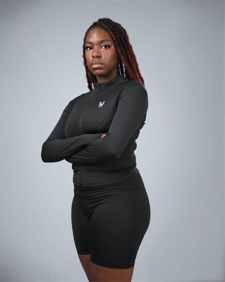 Person wearing a black athletic outfit with a logo on a gray background