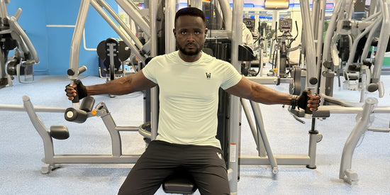 Man wearing athletic activewear t-shirt and gym pants while using chest press machine at fitness center