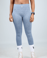 Person wearing blue leggings on a light gray background with waaka embroidery logo