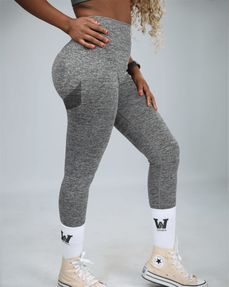 woman wearing gray leggings with waaka logo on white socks against a light grey background