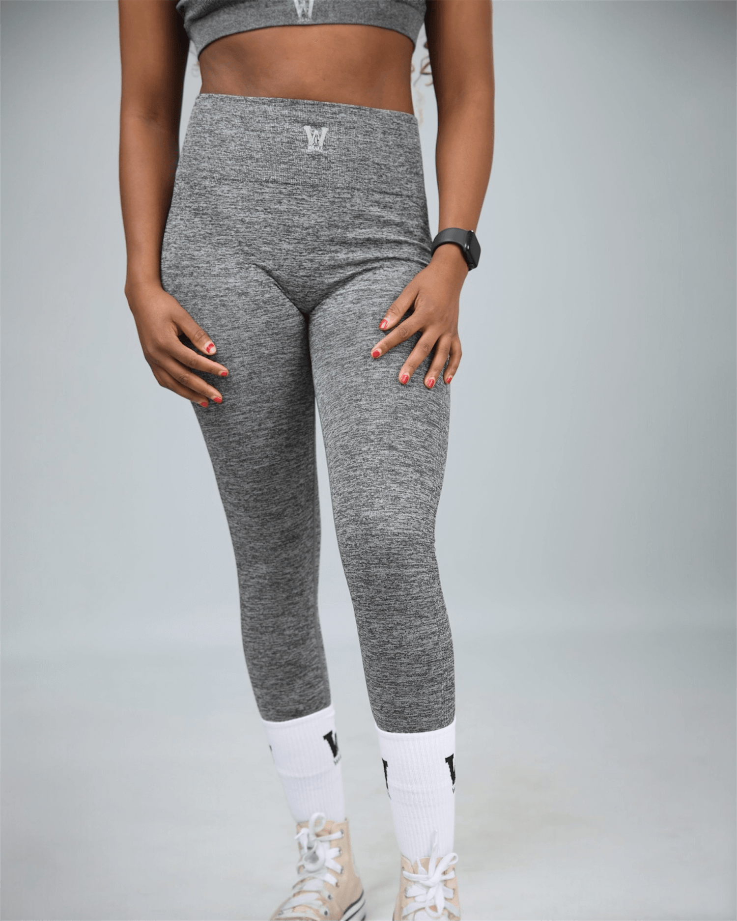 woman wearing gray leggings with waaka logo on white socks against a light grey background posing