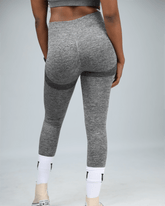 Person wearing gray leggings on a plain background back view