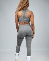 woman wearing gray leggings with waaka logo on white socks against a light grey background back view