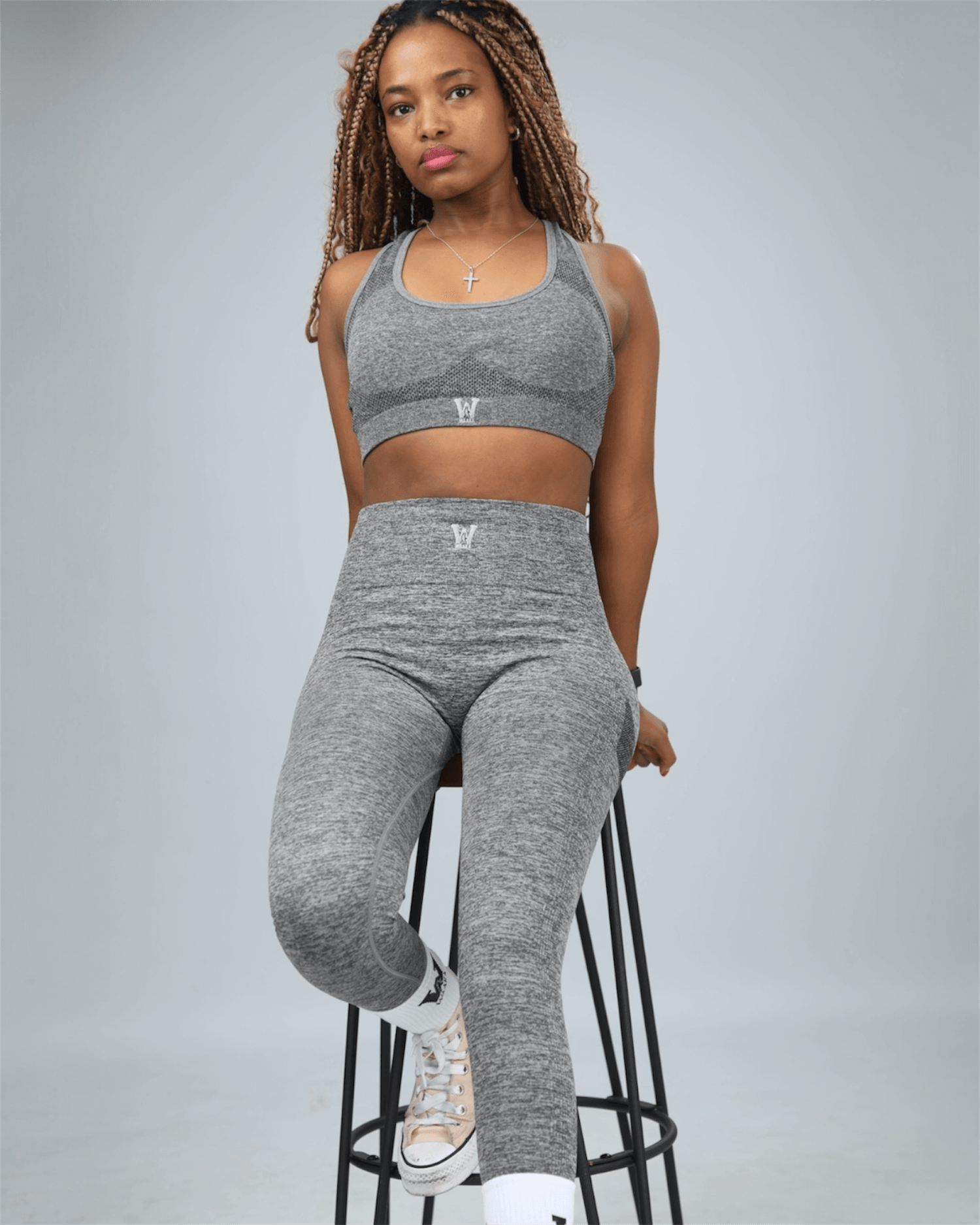 Woman wearing a gray athletic outfit on a gray background