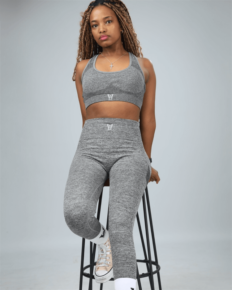 Woman wearing a gray athletic outfit on a gray background