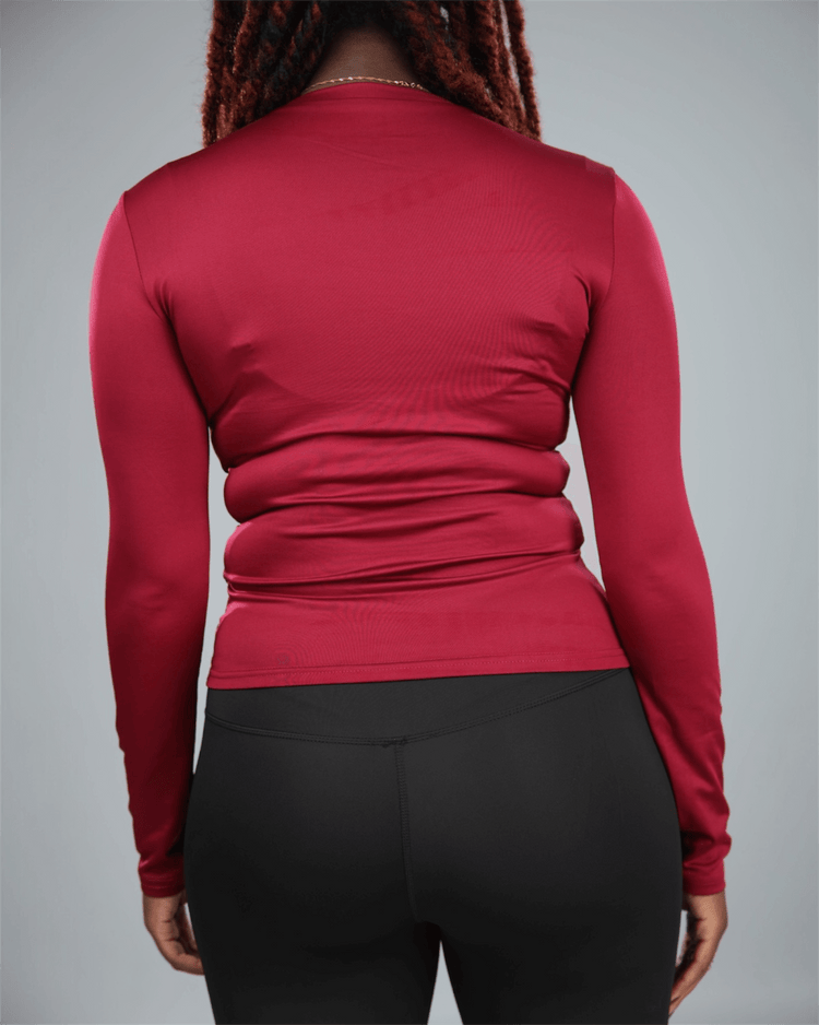 Person wearing a red long-sleeve top and black pants on a gray  background back view