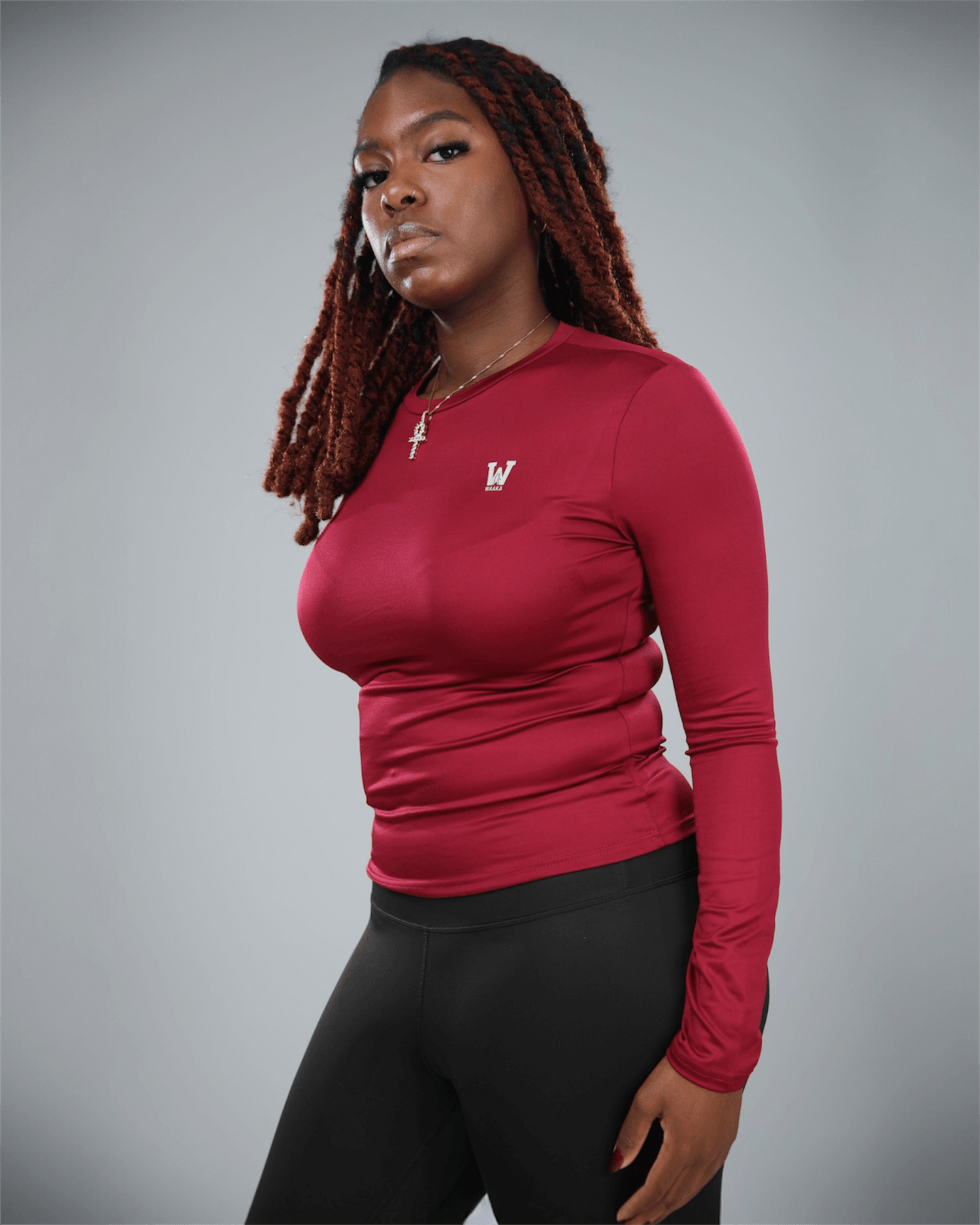 Woman wearing a red long-sleeve top with a logo on a gray background