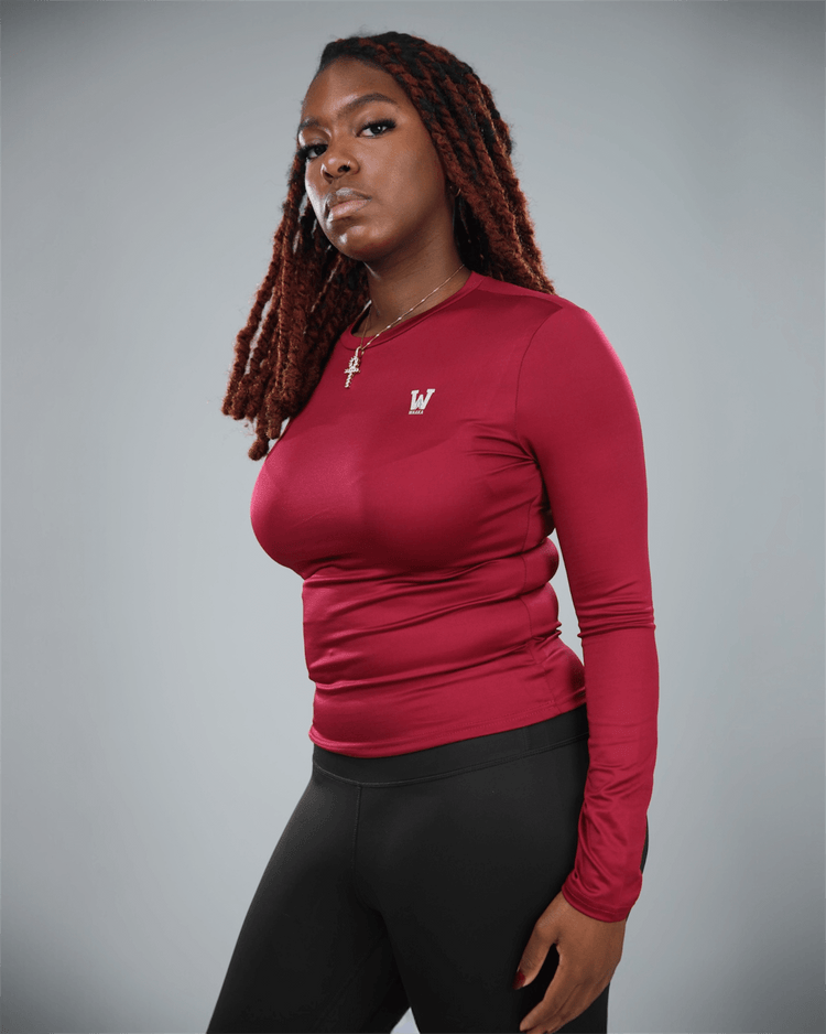 Woman wearing a red long-sleeve top with a logo on a gray background