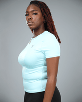 woman wearing a light blue athletic shirt with waaka logo on a grey background side view