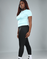 Person wearing a light blue top and black leggings on a gray background