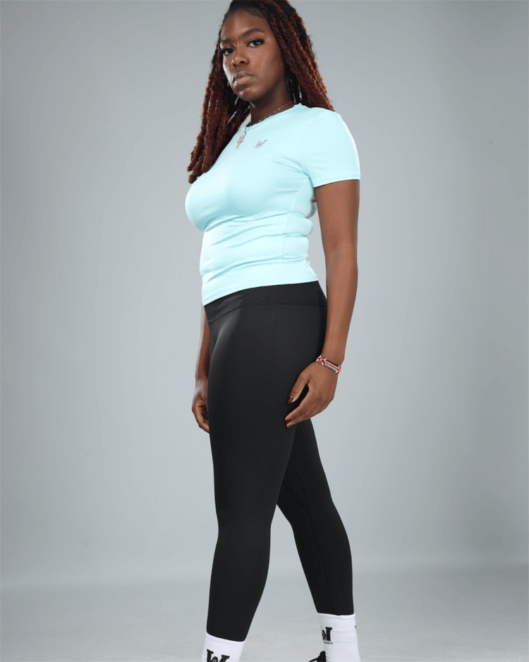 Person wearing a light blue top and black leggings on a gray background