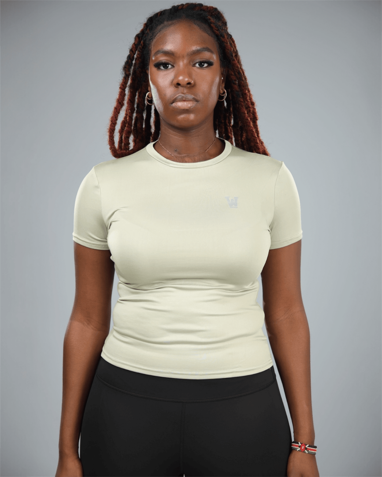 Person wearing a olive green athletic shirt with a logo on a gray background