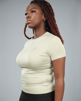 Woman wearing an olive green t-shirt and black leggings against a grey background side view