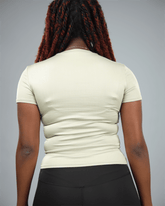 Woman wearing an olive green t-shirt and black leggings against a grey background back view