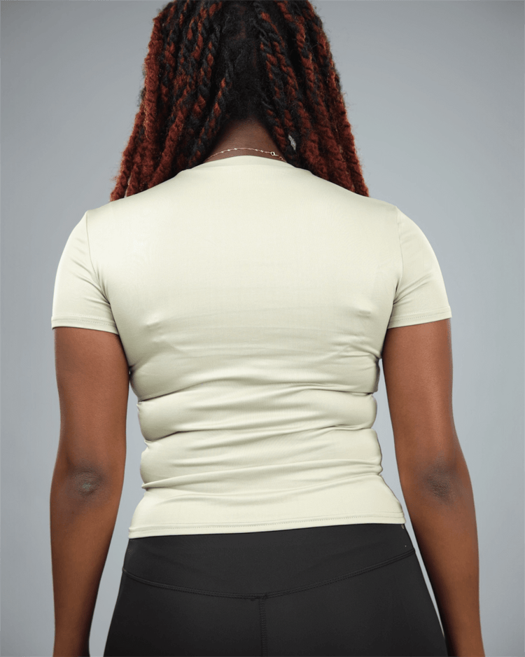 Woman wearing an olive green t-shirt and black leggings against a grey background back view