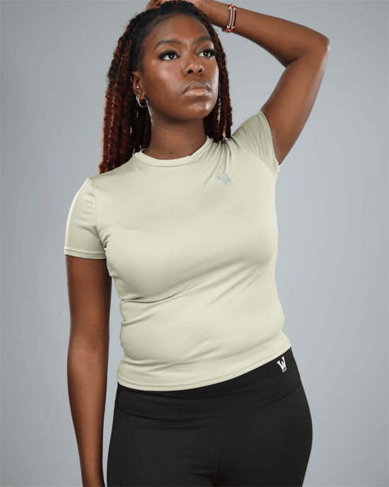 Woman wearing an olive green t-shirt and black leggings against a grey background