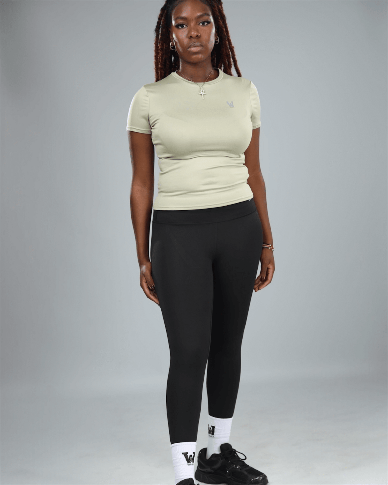 Person wearing a light green t-shirt and black leggings on a gray background