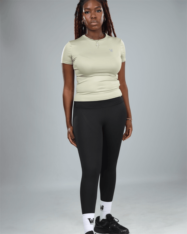 Person wearing a light green t-shirt and black leggings on a gray background