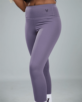 Purple leggings with waaka logo on a grey background