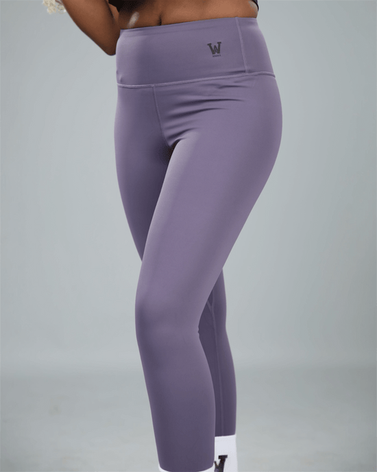 Purple leggings with waaka logo on a grey background