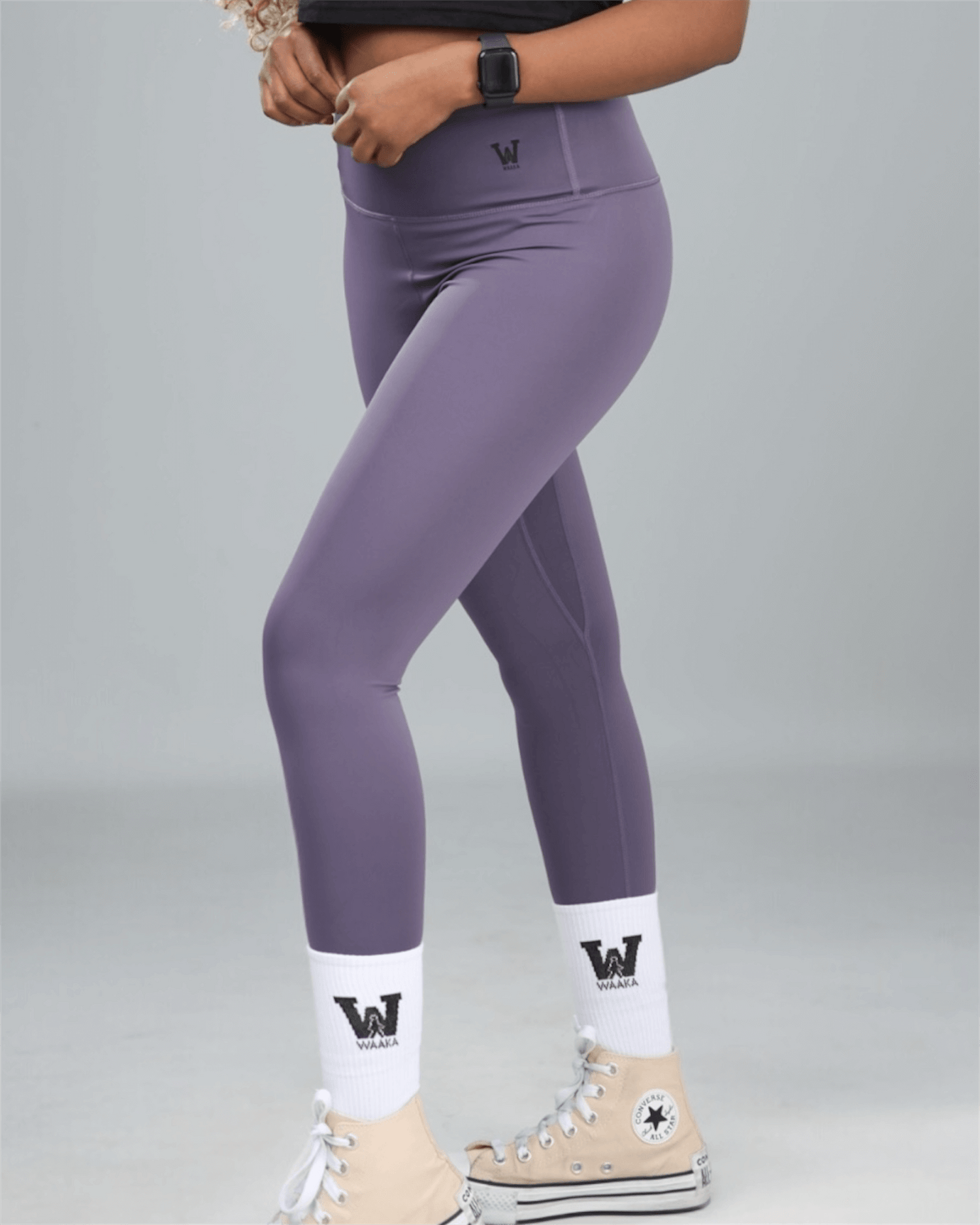 Person wearing purple leggings with a logo on a gray background