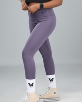 Person wearing purple leggings with a logo on a gray background