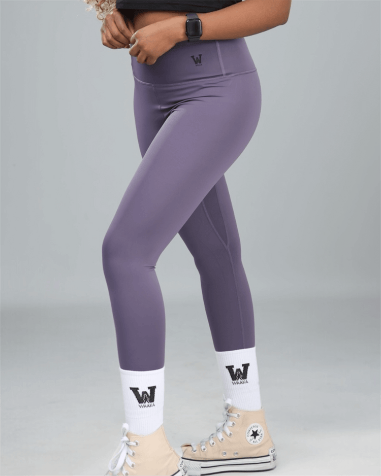 Person wearing purple leggings with a logo on a gray background