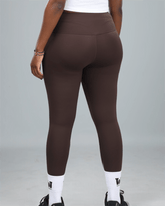 woman wearing brown gym leggings with waaka logo on a grey background with waaka socks