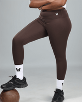 Person wearing brown leggings with waaka logo on a gray background