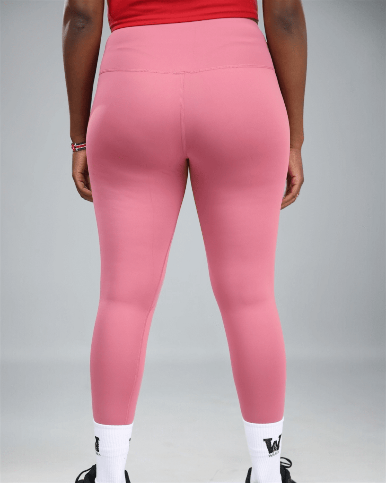 mauve Pink leggings with a logo on a grey background showing back view