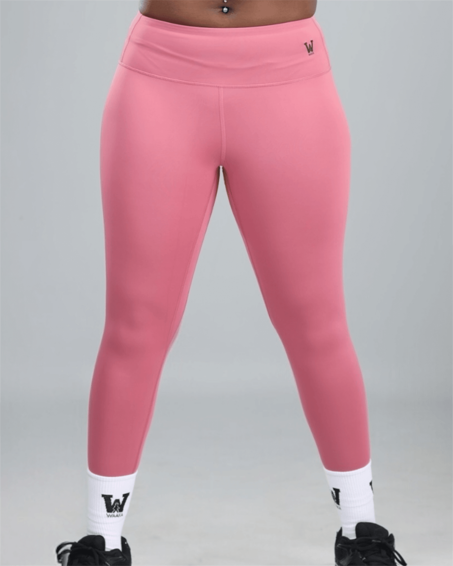 Pink leggings with white socks and black shoes on a gray background