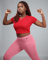 Person wearing a red crop top and pink leggings on a gray background