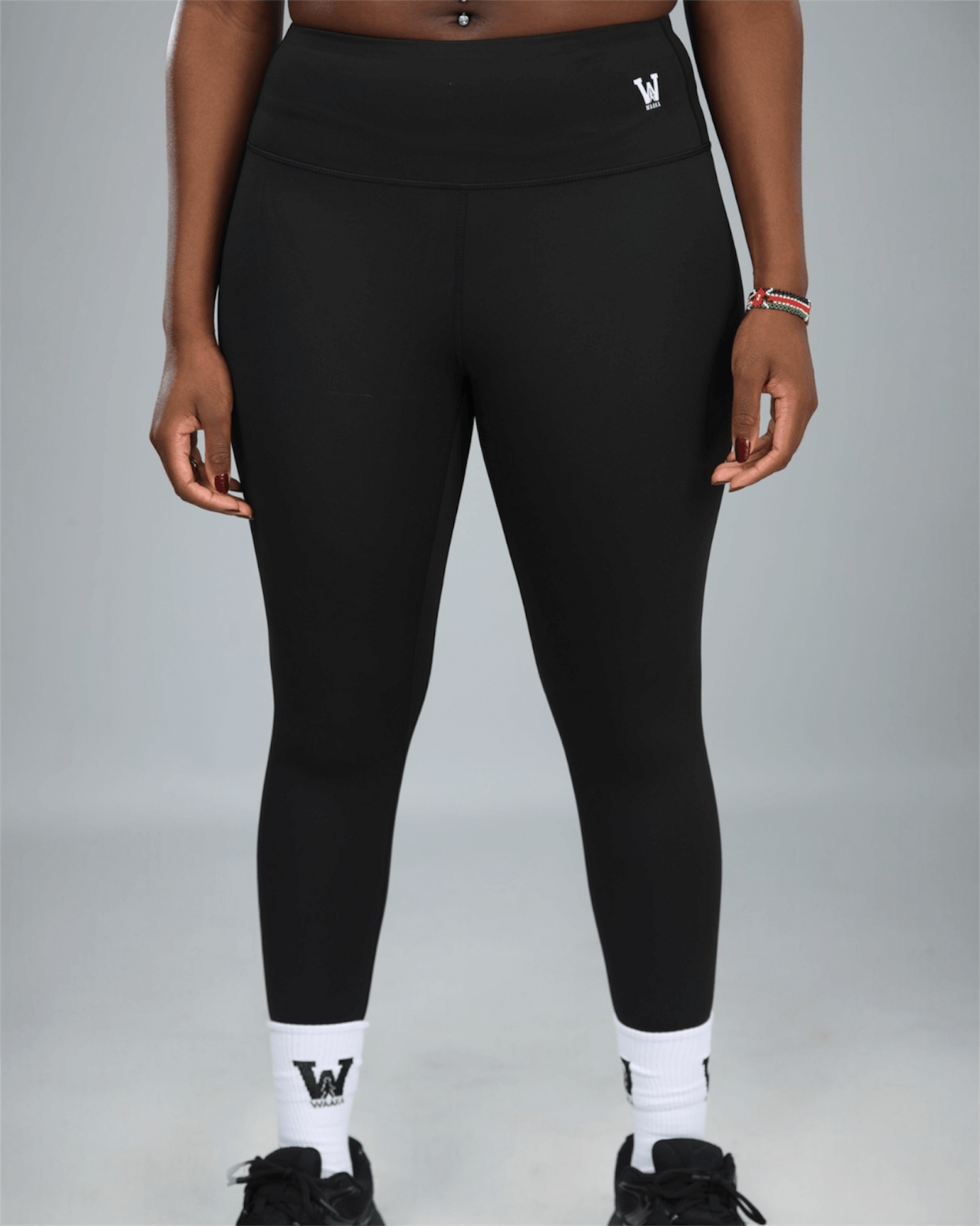 Person wearing black leggings with a logo on a gray background