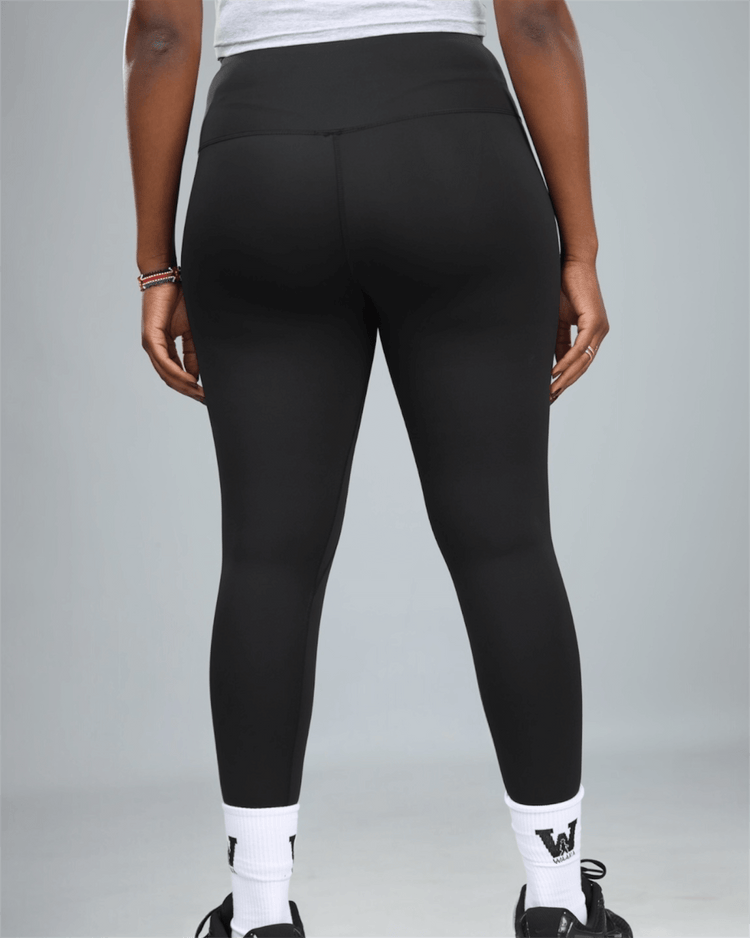 Person wearing black leggings on a gray background