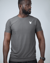 Man wearing a grey patterned activewear t-shirt with waaka logo on a light grey background - Surge