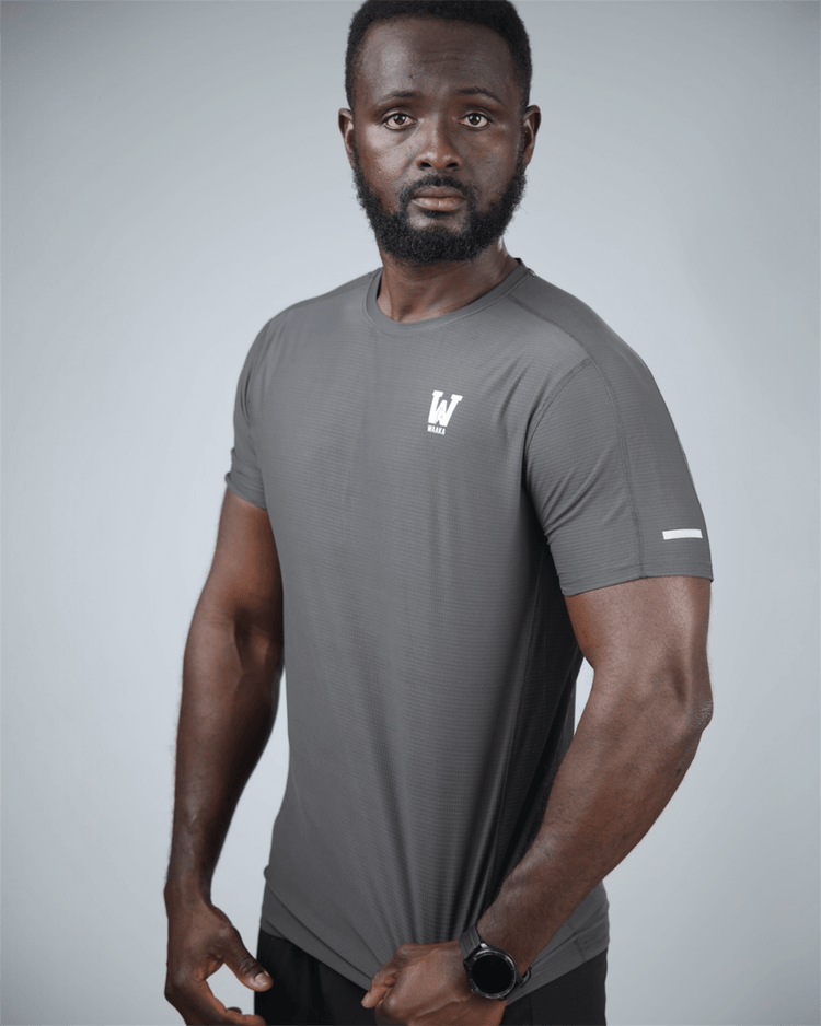 Man wearing a gray athletic t-shirt with a logo on a light gray background