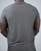 Man wearing a grey patterned activewear t-shirt with waaka logo on a light grey background back view - Surge