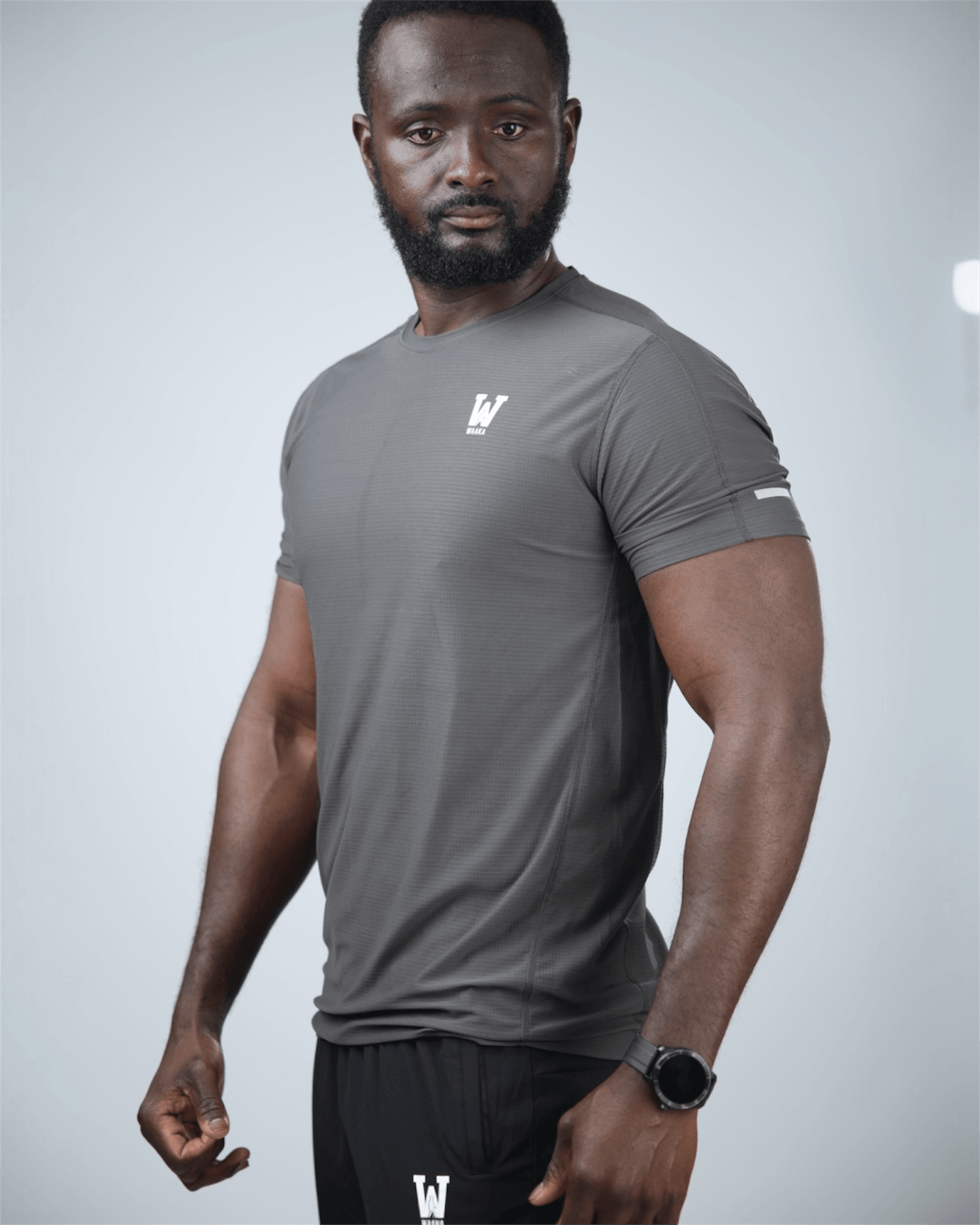 Man wearing a grey surge patterned athletic shirt with waaka logo on a light grey background