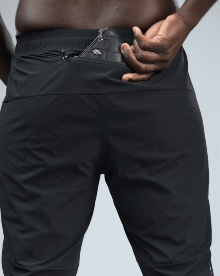 Person wearing black pants with a focus on the waist area and back pocket