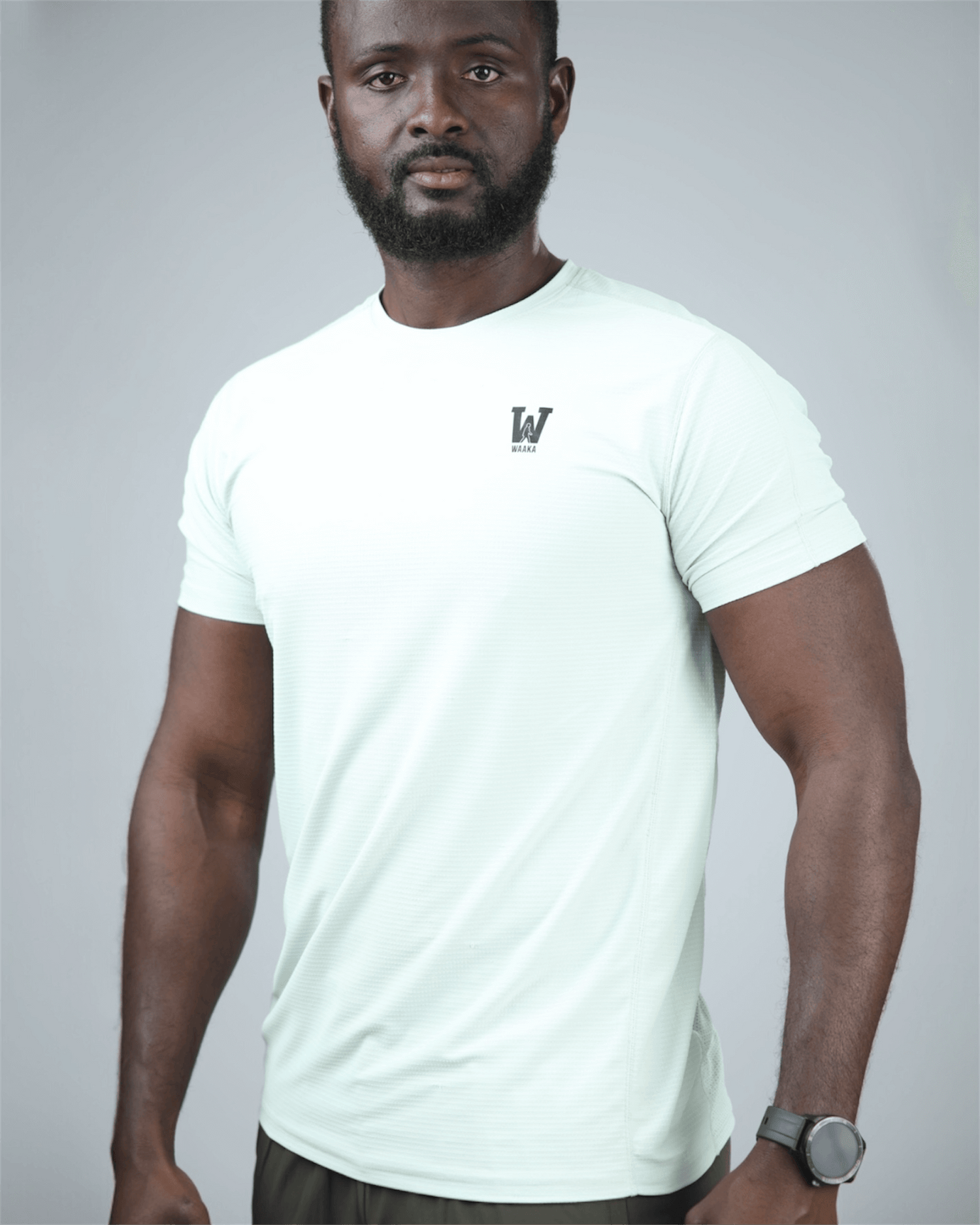 Man wearing a light green t-shirt with waaka logo on a grey background. surge patterned activewear