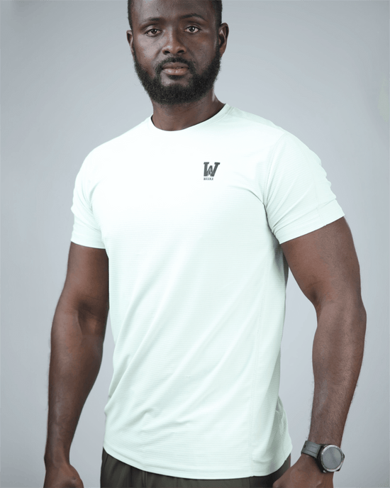 Man wearing a light green t-shirt with waaka logo on a grey background. surge patterned activewear