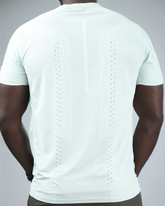 Man wearing a light green t-shirt with waaka logo on a grey background. surge patterned activewear back view