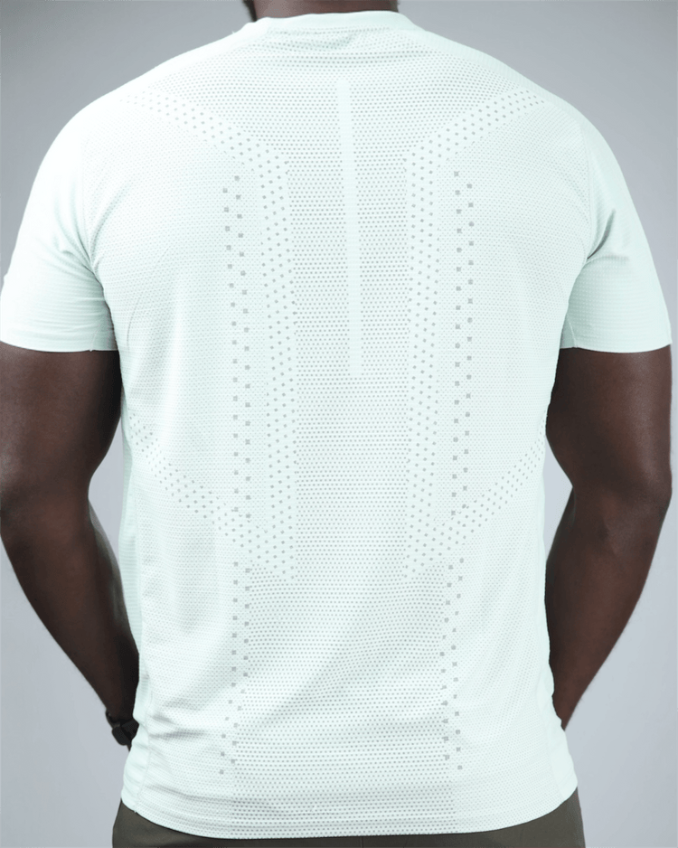 Man wearing a light green t-shirt with waaka logo on a grey background. surge patterned activewear back view