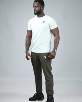 Man wearing a light green t-shirt and olive green pants on a gray background