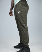 khaki green pants with waaka logo on a grey background side view. core performance pant