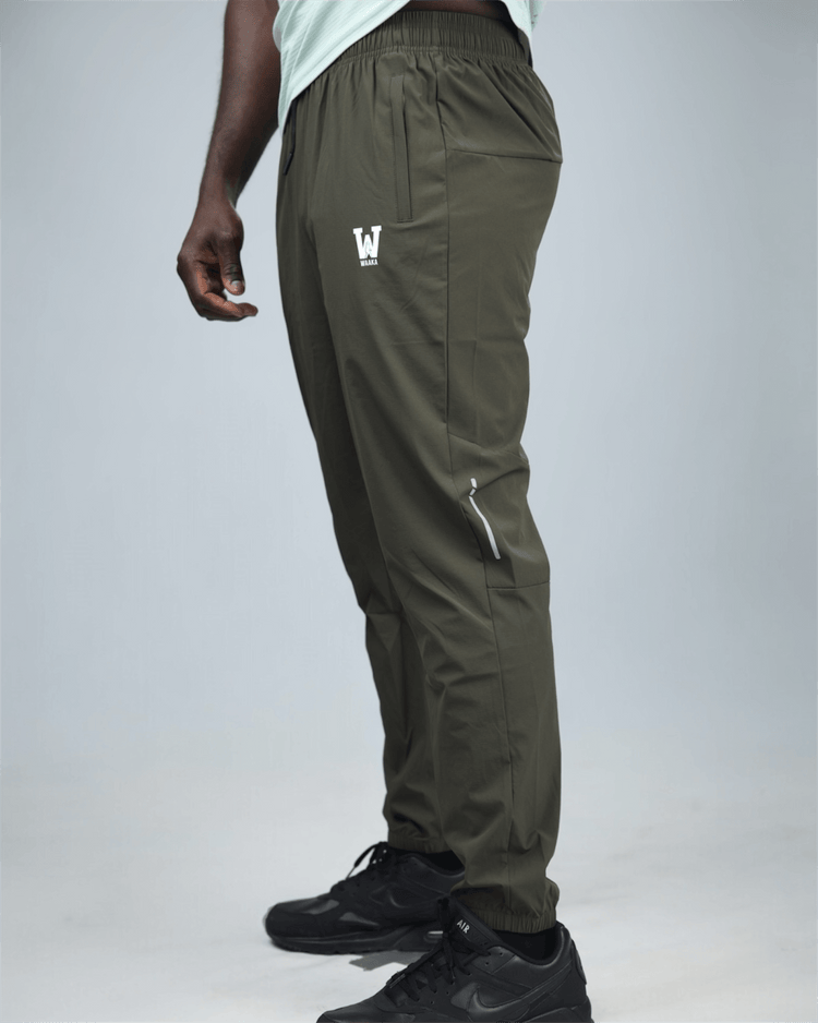 khaki green pants with waaka logo on a grey background side view. core performance pant